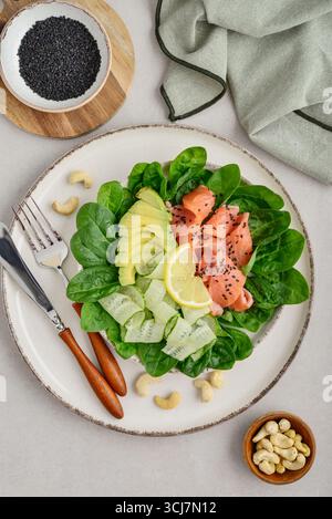 Lachssalat für ketogene Diät mit Avocado, Spinat, Gurke, Cashewnüssen auf hellem Hintergrund, Draufsicht Stockfoto
