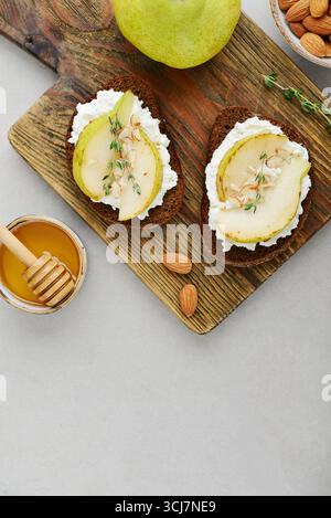 Bruschetta mit Frischkäse, Honig, Birne, Thymian auf hellem Hintergrund, Blick von oben. Stockfoto