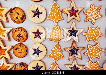 Eine Auswahl an festlichen Plätzchen mit verschiedenen Formen wie Sternen, Kreisen und Weihnachtsbäumen, dekoriert mit Glasur und Marmelade Füllung. Stockfoto