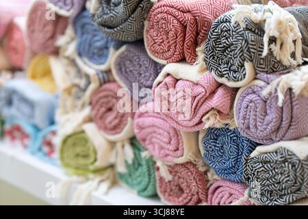 Nahaufnahme eines Stapels bunter, gemusterter Handtücher, ordentlich gerollt und in einem Geschäft ausgestellt. Hochwertige Fotos Stockfoto