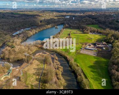 Panoramablick auf die üppige grüne Landschaft, gewundene Flüsse und die entfernte Skyline der Stadt bei Tageslicht Stockfoto