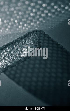 Nahaufnahme der Luftpolsterfolie, die geometrische Schatten auf einer Oberfläche erzeugt. Abstrakte Minimaltextur bei monochromem Licht. Stockfoto