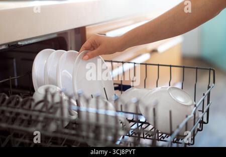Eine Unbekannte Frau, Die Sauberes Geschirr Aus Der Spülmaschine In Der Küche Ablädt Stockfoto