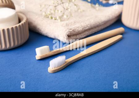 Bambus-Zahnbürsten mit Wattepads und Handtuch auf blauem Hintergrund, Großaufnahme Stockfoto