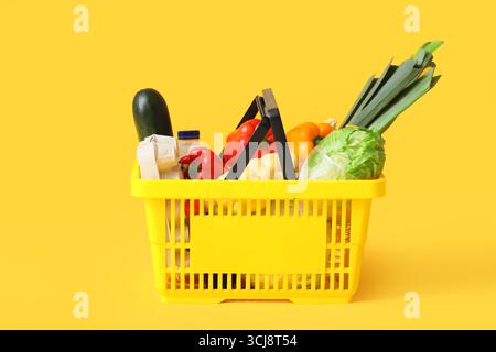 Warenkorb mit verschiedenen frischen Produkten auf gelbem Hintergrund Stockfoto