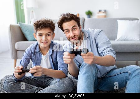 Gemütliches Familienwochenende. Überglücklich Vater und Sohn im Wettbewerb in Online-Videospielen, verbringen Zeit zusammen zu Hause Stockfoto
