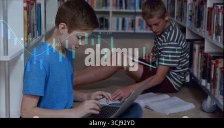 Lernen Sie Jungen beim Tippen und Lesen in Bücherregalen, mit Laptoplehrbüchern Stockfoto