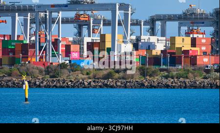 Port Melbourne, Victoria, Australien - 18. Juli 2025: Große Stapel von Frachtcontainern am Webb Dock mit gelber Boje im Vordergrund Stockfoto