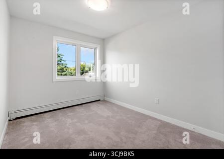 Sehr sauberes und leeres Schlafzimmer mit Fenster. Das Zimmer ist sehr hell und luftig. Das Fenster ist offen und lässt viel natürliches Licht herein Stockfoto