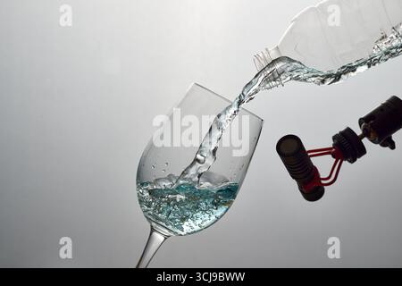 Ein Hochgeschwindigkeitsfoto von Süßwasser, das in ein Glas gegossen wird, das mit einem Mikrofon aufgenommen wurde. Ein vielseitiges Konzept für ASMR, Hydration, Reinheit und Umgebung Stockfoto