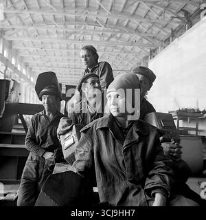 Eine Brigade von Schweißern, geführt von einer jungen Frau, posiert für ein Porträt in einer Werkstatt eines Maschinenbauwerks (Stroymash oder Maschmet) in Sloviansk, 1970er Jahre Das Archivfoto im Stil des sozialistischen Realismus verherrlicht kollektive Arbeit und das Bild einer Sowjetfrau, die einen männlichen Beruf beherrschte. Dieses Foto ist ein Symbol für die industrielle Macht und das friedliche kreative Leben im Donbass vor dem Krieg Stockfoto