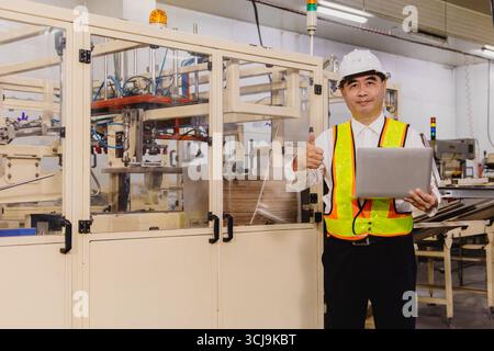Portrait Erwachsener asiatischer Ingenieur Supervisor Mann, der glücklich lächelnd in der Transportlinie der Fabrik steht Stockfoto