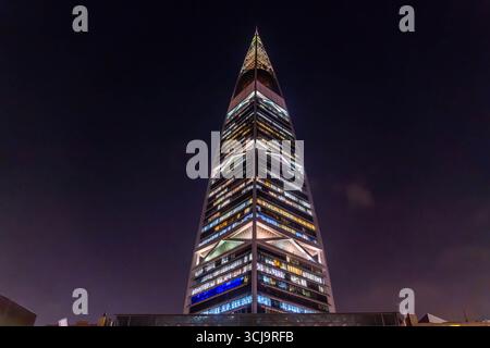 Der nächtliche Blick auf den Al Faisaliah Tower in Riad, Saudi-Arabien, erhebt sich mit seiner unverwechselbaren goldenen Kugel in der Nähe des Gipfels, umgeben von Palmen Stockfoto