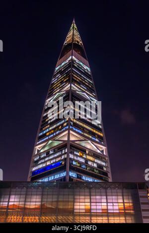 Der nächtliche Blick auf den Al Faisaliah Tower in Riad, Saudi-Arabien, erhebt sich mit seiner unverwechselbaren goldenen Kugel in der Nähe des Gipfels, umgeben von Palmen Stockfoto