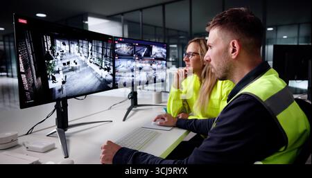 Besetzte Überwachungsbeamte überprüfen das Videomaterial der CCTV-Sicherheitskamera auf Bildschirmen Stockfoto