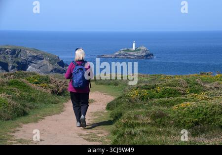 Frau geht zum Godrevy Island Lighthouse auf dem Cliff Path von Godrevy Point in der Nähe von Hayle am Southwest Costal Path, Cornwall, England, Großbritannien. Stockfoto