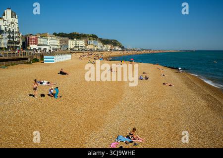 Sonnenanbeter am Strand von Hastings an einem sonnigen englischen Sommertag in Hastings, East Sussex, England Stockfoto