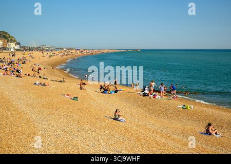 Sonnenanbeter am Strand von Hastings an einem sonnigen englischen Sommertag in Hastings, East Sussex, England Stockfoto