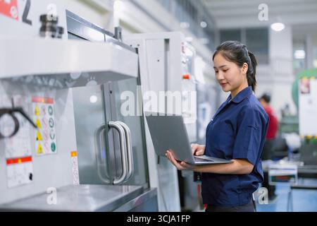 Junge Techniker Ingenieurarbeiterinnen arbeiten mit CNC-Drehmaschine in modernen Stahlindustriefabriken Stockfoto