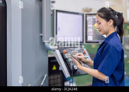 Junge Techniker Ingenieurarbeiterinnen arbeiten mit CNC-Drehmaschine in modernen Stahlindustriefabriken Stockfoto
