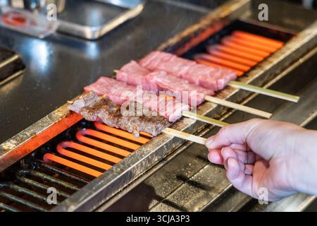 Auf dem Straßenmarkt grillen Sie das köstliche hida-Rindfleisch mit hoher Marmorierung an Spießen. Stockfoto