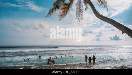 Sonnige Strandszene mit Menschen, die die Wellen spielerisch genießen Stockfoto
