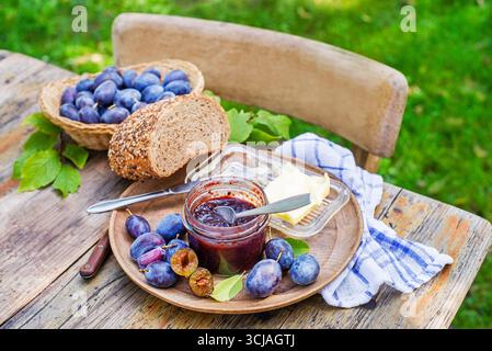 Pflaumenmarmelade oder Marmelade in einem Glas mit Pflaumenobst im Freien an sonnigen Tagen Stockfoto