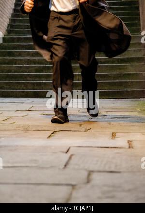Eine Person in einem Anzug läuft eine Treppe hinunter. Stockfoto