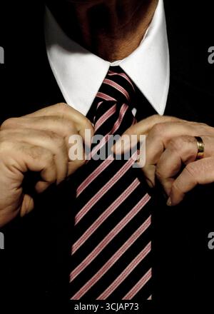 Ein Mann im Anzug passt seine Krawatte an. Stockfoto