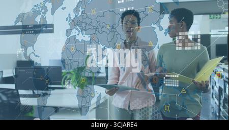 Überprüfung der digitalen Kartenüberlagerung zwei Frauen analysieren Daten auf Tablets und Ordnern im Großraumbüro Stockfoto