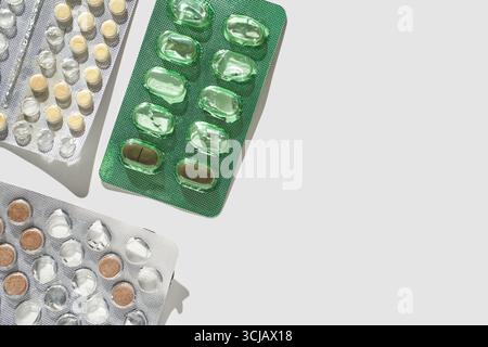 Gemischte Blisterpackungen mit grünen und gelben Pillen auf hellgrauem Hintergrund mit Schatten. Stockfoto