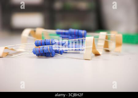 Blaue Widerstände mit Farbbändern in Reihe auf weißer Oberfläche Stockfoto
