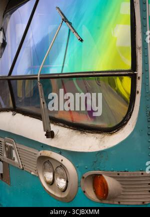 Nahaufnahme des alten Retro-Bus-Frontscheibenwischerblatts und der linken Frontscheinwerfer zwei runde klare Leuchten und eine runde orange helltürkisfarbene Busblau gre Stockfoto