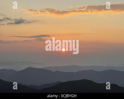 Warmes Sonnenlicht, das schneebedeckte Bergkämme umspült, goldenes Licht, das mehrschichtige Gipfel über die weitläufige Wildnislandschaft freigibt Stockfoto