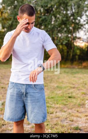 Athlet überprüft die Zeit auf Smartwatch nach dem Training im Park Stockfoto
