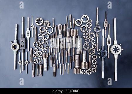 Gewindebohrer, Matrizen und Schraubenschlüssel für Gewindebohrer und Matrizen auf schwarzem Hintergrund. Manuelles Gewindewerkzeug. Stockfoto