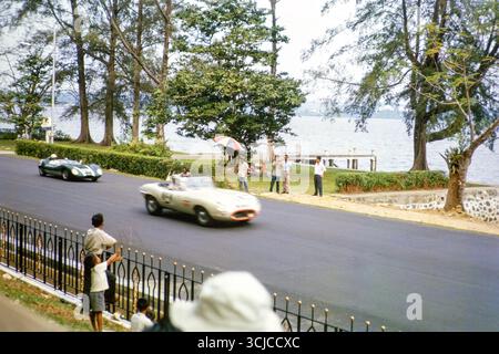 Jaguar E-Type Auto, das vermutlich von Freddie Johns und Lola Mk1 gefahren wird, die am 2. September 1963 beim Formule Libre Johore Grand Prix in Johor Bahru, Malaysia, teilnahmen Stockfoto