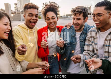 Eine junge Gruppe von Freunden der verschiedensten Generation, die Spaß beim Feiern mit Funkeln haben Stockfoto