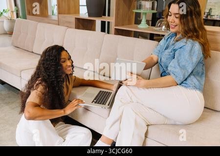 Zwei Kollegen führen in einer modernen Büroumgebung eine lebhafte Diskussion. Sie sitzen bequem, mit einem Laptop und Tablet und zeigen Teamgeist Stockfoto
