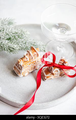 Festliche Lebkuchenkekse in Form von Fahrzeugen mit Weihnachtsbaumschmuck. Diese Cookies werden durch ein rotes Band verstärkt und auf einer strukturierten Platte platziert Stockfoto