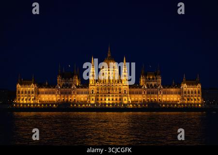 Atemberaubender nächtlicher Blick auf Budapests Parlamentsgebäude, wunderschön beleuchtet und reflektiert auf der Donau und zeigt komplexe Architektur Stockfoto