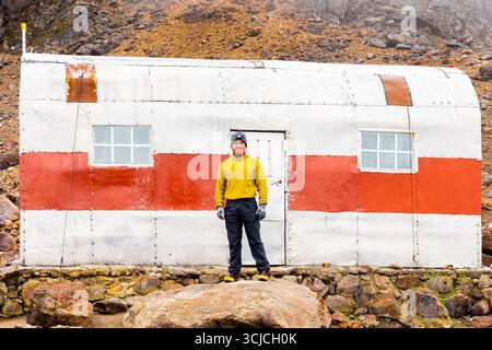 Ein Mann in einer gelben Jacke steht vor einem Metall-Bergheim in Iztaccihuatl, Mexiko. Die Schutzhütte ist weiß gestrichen mit einem roten Streifen, eingestellt Agave Stockfoto