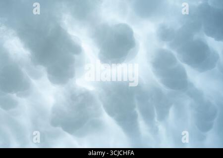 Ein ätherischer Blick auf den Himmel mit abstrakten Wolkenformationen in sanften Grautönen. Das flauschige, bewölkte Erscheinungsbild schafft ein ruhiges und ruhiges Ambiente Stockfoto