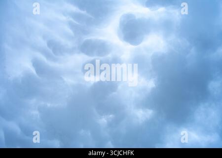 Ein ätherischer Blick auf den Himmel mit abstrakten Wolkenformationen in sanften Grautönen. Das flauschige, bewölkte Erscheinungsbild schafft ein ruhiges und ruhiges Ambiente Stockfoto