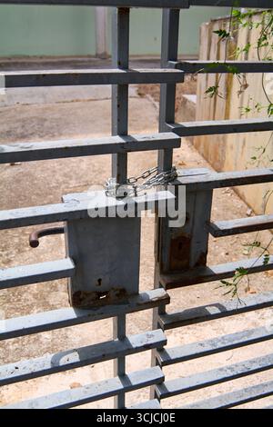 Eine detaillierte Nahaufnahme eines rostigen Metalltors mit einer Kette und einem Schlüsselloch, die Konzepte wie Sicherheit, Verschluss und Privatsphäre symbolisiert. Stockfoto