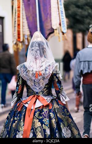 Frau in einem traditionellen Fallera-Kleid mit komplizierten Spitzendetails, Teilnahme am lebhaften Las Fallas Festival in Valencia, Spanien. Die farbenfrohe EV Stockfoto