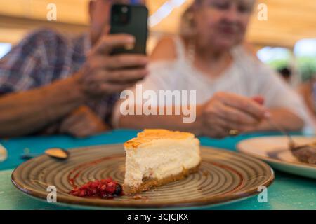 Glückliches Seniorenpaar, das einen herrlichen Käsekuchen in einem spanischen Restaurant genießt. Das warme Ambiente und die köstliche Küche sorgen für den perfekten Ruhestand Stockfoto