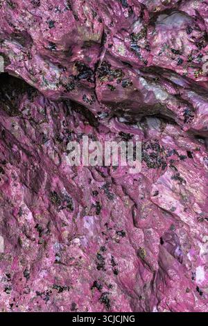 Ein beeindruckendes abstraktes Nahaufnahme-Bild mit leuchtenden rosa und violetten Felsstrukturen in einer Höhle. Die komplizierten Muster und Farbvarianten Stockfoto
