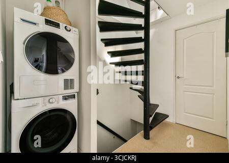 Ein moderner Blick mit einer Wendeltreppe, die zu einem gut organisierten Waschbereich führt, kombiniert Funktionalität mit modernen Designelementen Stockfoto