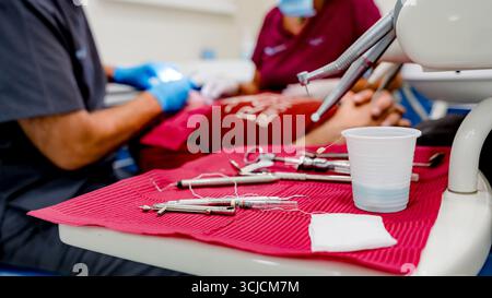 Eine Sammlung von Implantatwerkzeugen wird auf einer roten Matte in einer klinischen Umgebung angezeigt, die für einen zahnärztlichen Eingriff bereit ist. Die Einstellung schlägt einen Profi vor Stockfoto